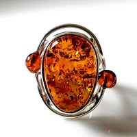 The central focus of the ring is a sizable oval-shaped amber gemstone.