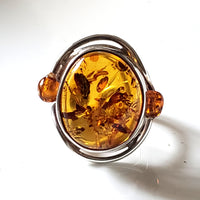 Natural amber ring with small amber beads on each side of the main stone. Ring set in sterling silver frame.