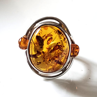 Natural amber ring with small amber beads on each side of the main stone. Ring set in sterling silver frame.