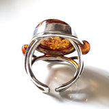 genus amber ring with small amber beads on each side of the main stone. ring set in sterling silver frame.