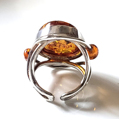genus amber ring with small amber beads on each side of the main stone. ring set in sterling silver frame.