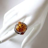 Natural honey amber ring with small amber beads on each side of the main stone. ring set in sterling silver frame.