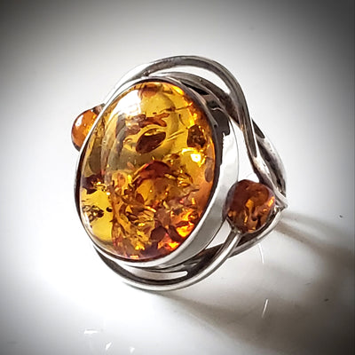 genus amber ring with small amber beads on each side of the main stone. ring set in sterling silver frame.