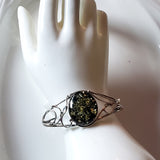  silver bracelet with oval green amber on display hand