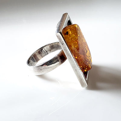 side of ring, large rectangle sterling silver frame with free form natural amber inside the frame 