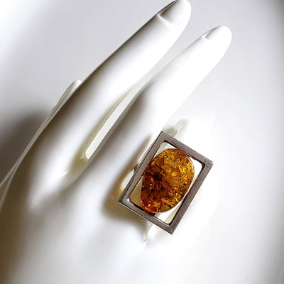 large sterling silver ring with amber on a hand display