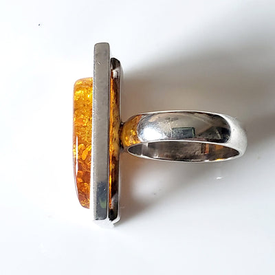 side of Unisex ring, large rectangle sterling silver frame with free form natural amber inside the frame 