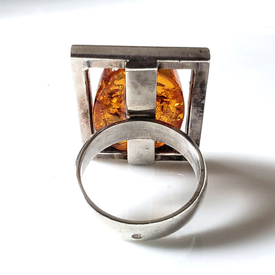 back of Unisex ring, large rectangle sterling silver frame with free form natural amber inside the frame. The 925 sterling silver frame is on a back of the ring frame